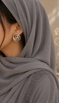 Close-up of a person wearing a gray hijab with a focus on an earring.